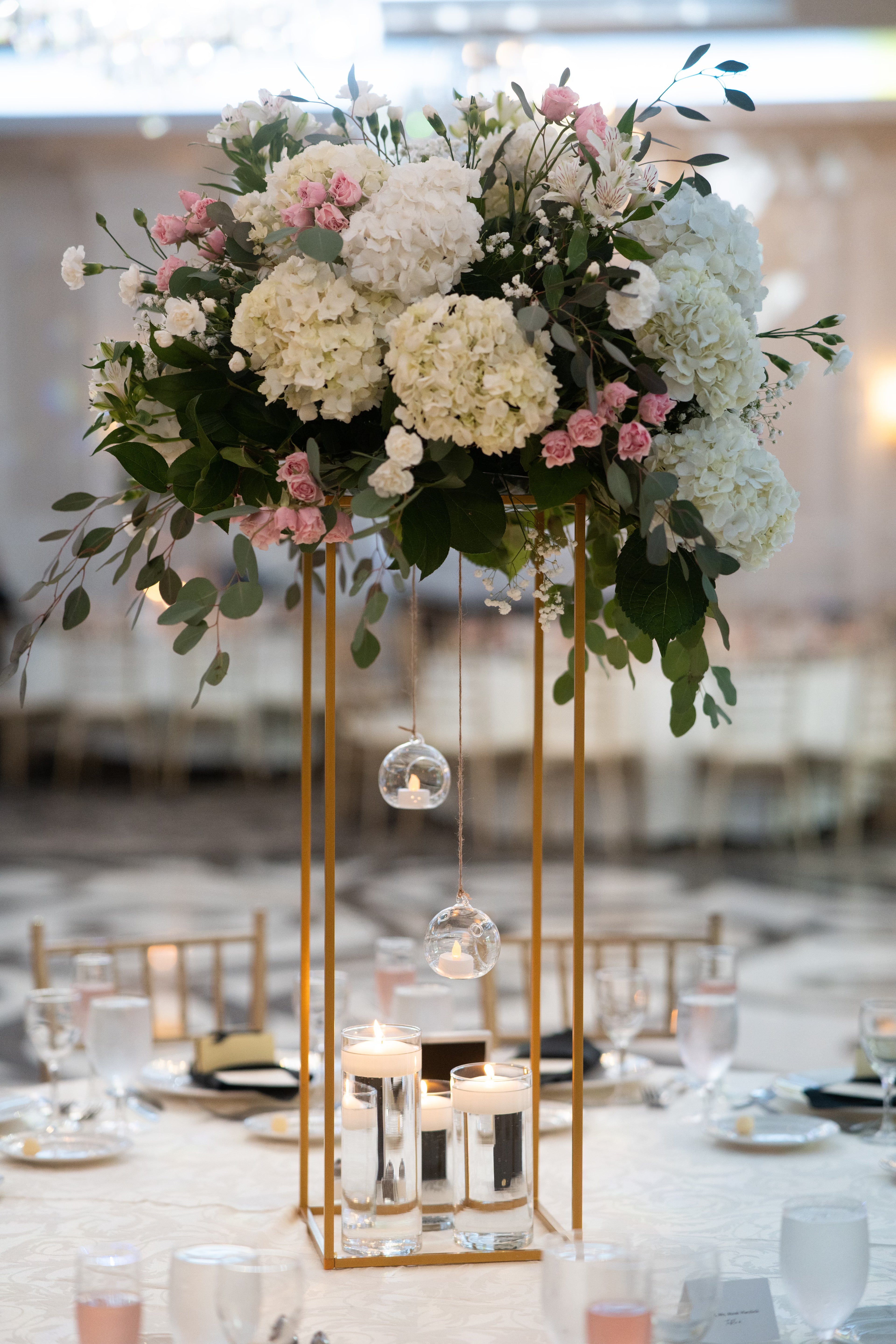 Decorative floral arrangement with hanging lights on a table setting.