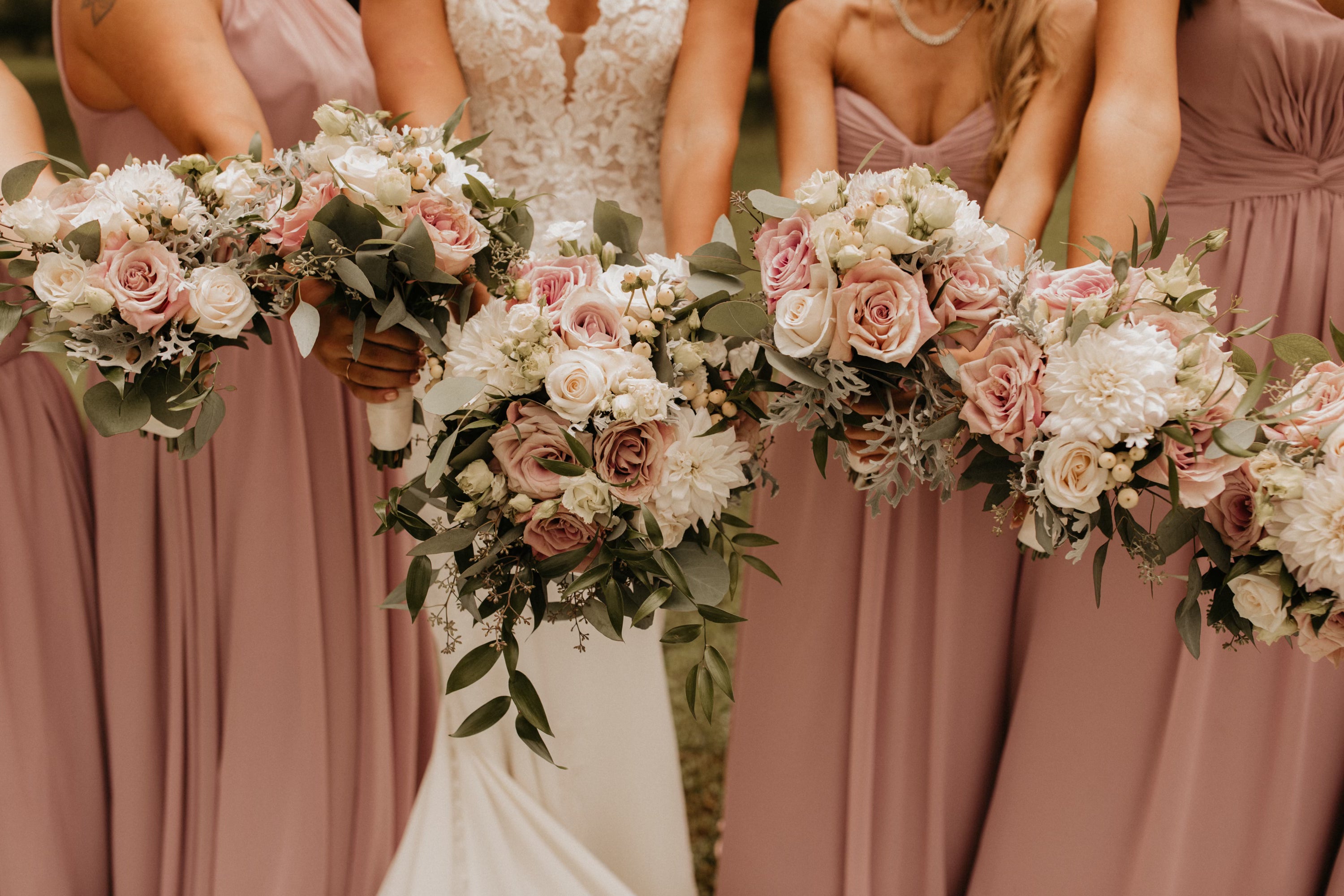 Bridesmaids in pink dresses holding floral bouquets with a bride in the center.